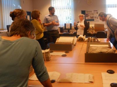 Volunteers gathered around a table of archive volumes and boxes in a search room