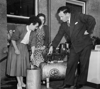 Black and white photograph of an ESB demonstrator showing two women how an electric water pump works