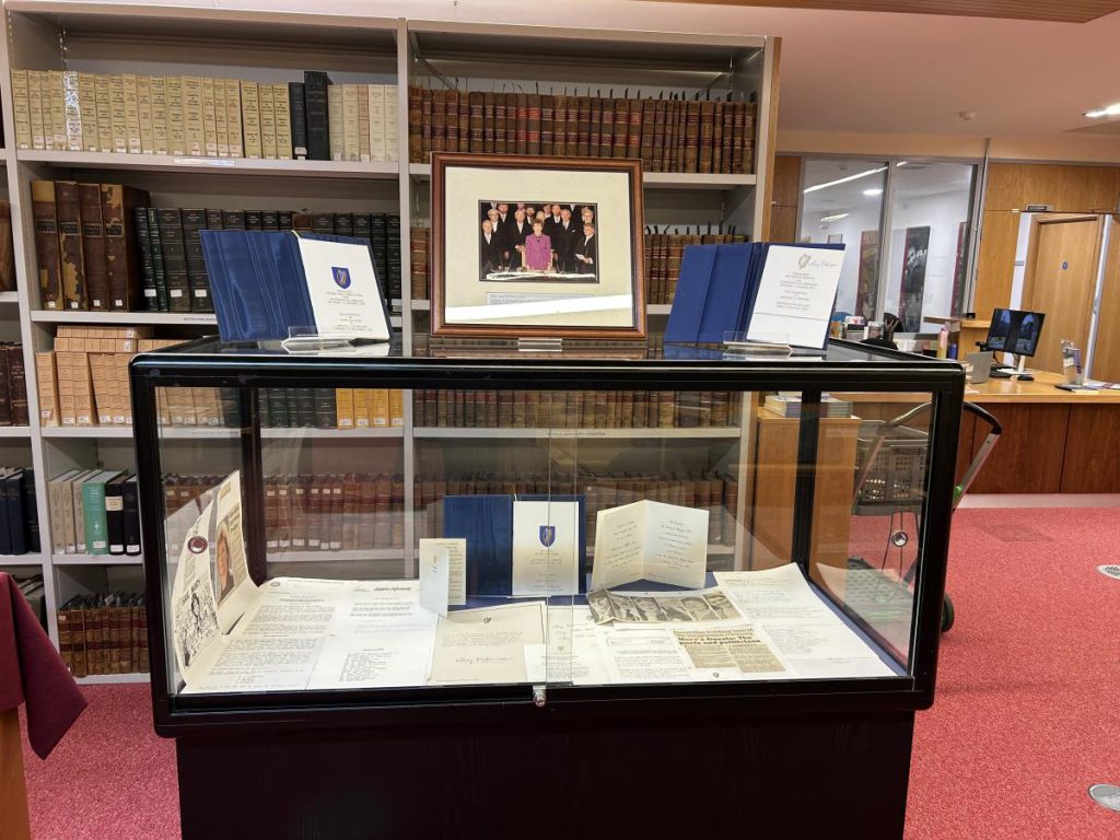 Display case of Mary Robinson inauguration material in a reading room, with a framed photograph on the shelves behind
