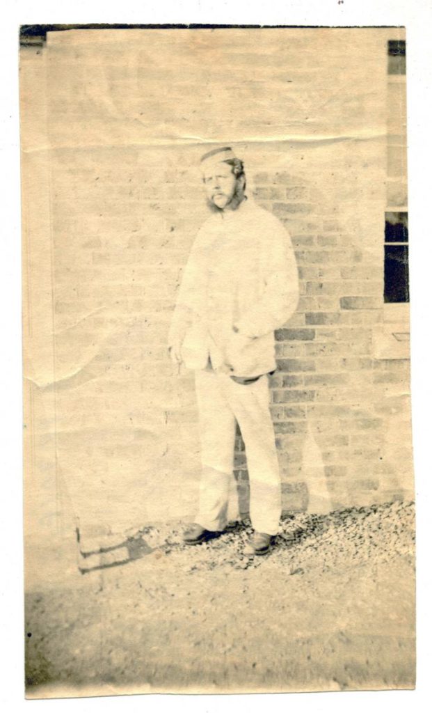Faded photograph of Henry Popham Tenison MacCarthy, son of Daniel MacCarthy and a captain in the Royal Artillery, standing beside a wall