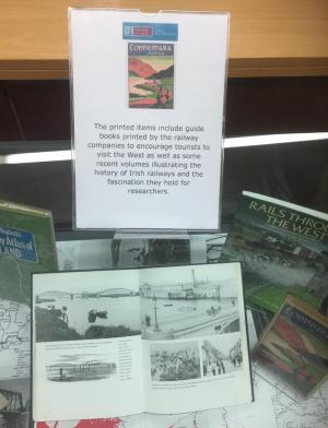 Exhibition case of railway guide books and an open book of photographs of trains and stations in the west of Ireland